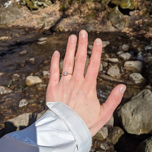 Yellow gold solitaire ring on hand by a creek