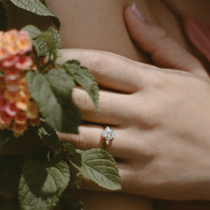 A floral arrangement and a petite three-stone engagement ring on hand