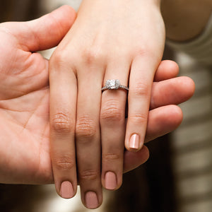 half bezel halo engagement ring on hand close up
