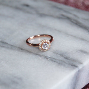 Rose gold halo engagement ring on marble