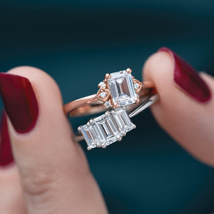Woman holds art deco inspired ring and three stone ring