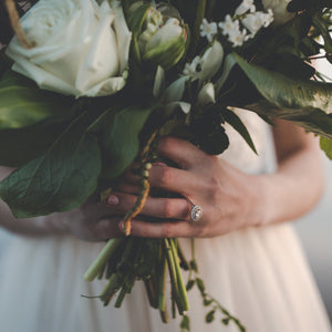 Bride wears double halo engagement ring and holds bouquet