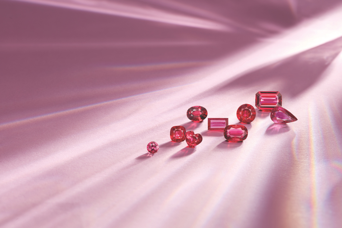 loose colored gemstones on pink background ruby engagement rings - blog post by Soha Diamond Co. Jewelry Store in Madison, WI