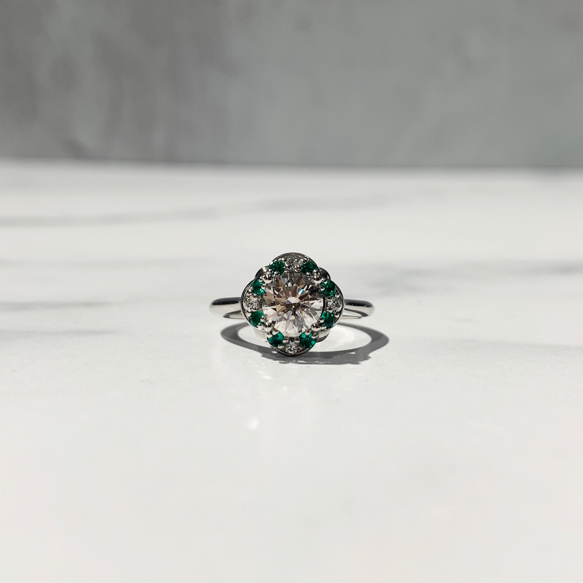 Halo engagement ring with emeralds and diamond halo