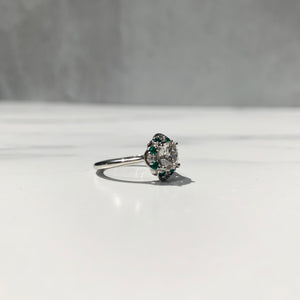 Side view of halo engagement ring with emerald and diamond