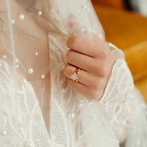 Bride wearing rose gold engagement ring and marquise wedding band
