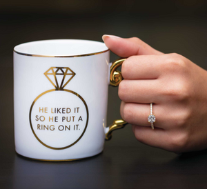 Hand holding coffee mug with yellow gold engagement ring