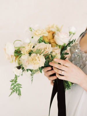 Woman holding flowers wearing three-stone ring