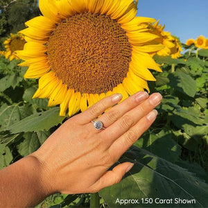 Round bezel set halo engagement ring on hand by sunflower
