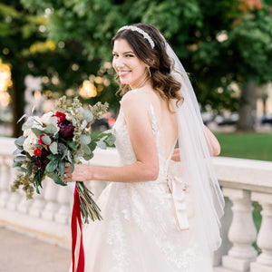 Bride smiles at the camera as she holds a bouquet