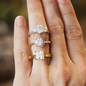 Three stone ring, rose gold halo, and yellow gold solitaire on hand